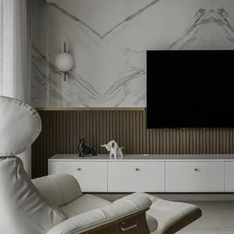 Book-matched marble TV wall whose grey veining mirrors into a chevron above a walnut fluted dado