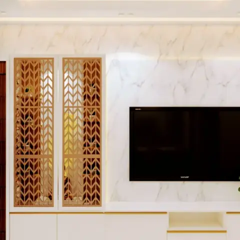 Book-matched white marble TV wall with a pair of tall gold chevron-jaali display shutters beside a dark rosewood flush door.