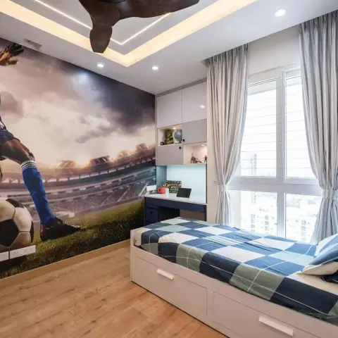 Boy's bedroom with a large football stadium mural wallpaper, a built-in study desk, and a storage bed dressed in blue check bedding