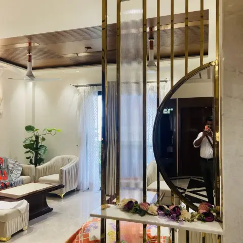 Brass-framed fluted-glass partition carrying a half-moon mirror and a marble shelf dressed with faux flowers
