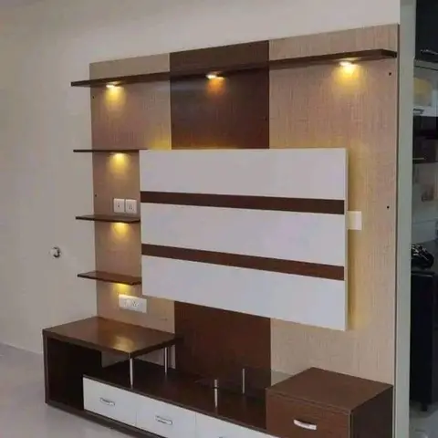 Brown-and-white laminate TV unit wall with spotlit floating display shelves and a lower drawer console
