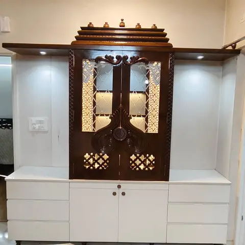 Built-in pooja unit with a carved dark-wood mandir cabinet featuring mirrored jaali-cut doors and backlighting