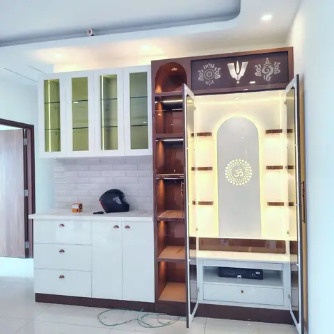 Built-in pooja unit with a backlit arched niche and an Om-motif frosted glass panel, open temple doors