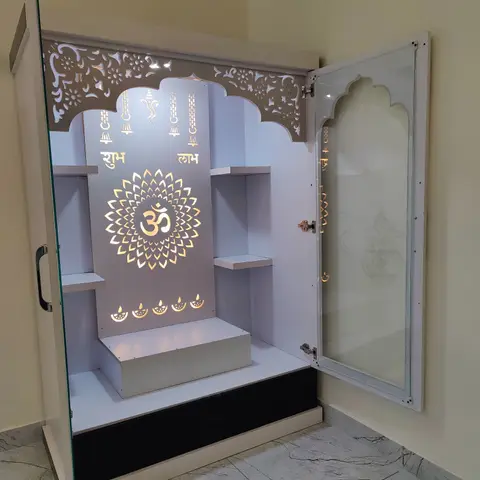Built-in pooja unit with a jharokha-arched CNC-cut crown, backlit Om motif panel, floating shelves and an etched-glass door.