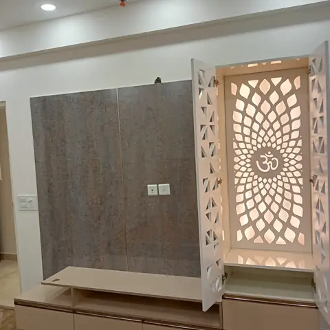 Built-in pooja unit with backlit CNC-cut white lotus-pattern jaali doors framing an Om symbol