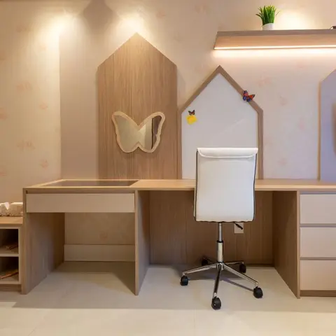 Built-in study desk with a house-shaped wood panel backdrop, a butterfly-cut mirror, and an LED-lit open shelf in a pastel kids' bedroom.