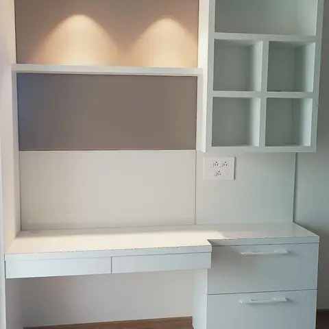 Built-in study desk with drawer storage, an open display cubby unit, and two pendant lights over a taupe accent backsplash.