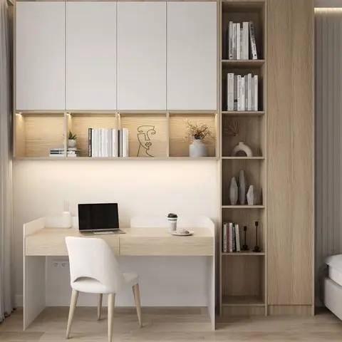 Built-in study nook with a floating white-and-oak desk, open display shelving lit by cove lighting, and a matching tall wardrobe beside the bed.