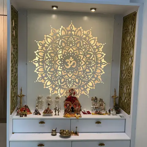 Built-in white pooja unit with a large CNC-cut mandala carrying an Om at its centre, backlit so the pattern glows against the rear panel