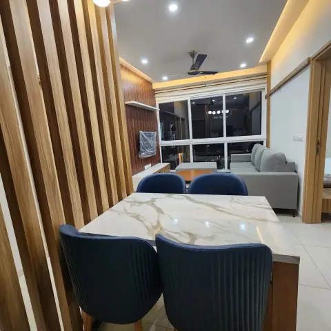 Calacatta-look dining top with four navy pleated chairs, lit by a brass linear pendant of opal globes and screened from the passage by floor-to-ceiling teak