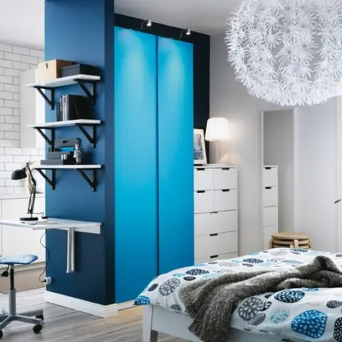 Catalog-style studio layout combining a white subway-tiled kitchenette, a blue wardrobe column with an integrated fold-down desk