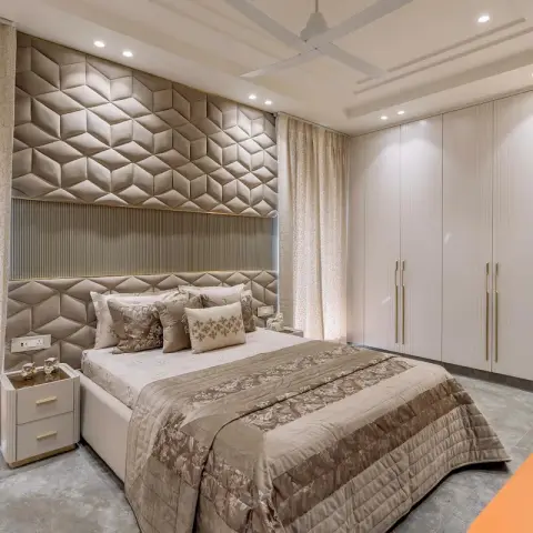 Champagne bedroom with a full-height hexagon-tufted faux-leather headboard wall over a fluted band, flanked by printed sheer drapes