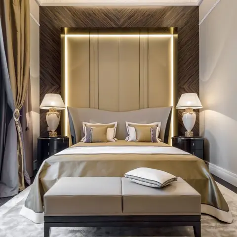 Champagne-satin bedroom with a tall padded headboard panel outlined by a concealed LED reveal, set into a chevron-laid dark ebony veneer wall