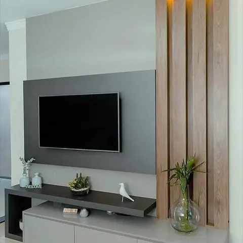 Charcoal-grey TV feature wall paired with a backlit vertical wood-fluted panel, styled with a ceramic bird and glass bud vase on the console