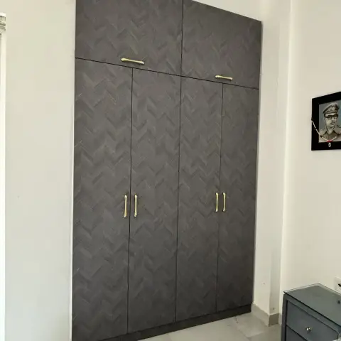 Charcoal herringbone-textured laminate wardrobe with separate loft shutters and cast brass drop handles