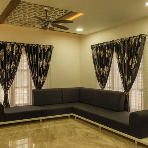 Charcoal L-shaped sectional sofa on a raised platform base in an empty living room corner