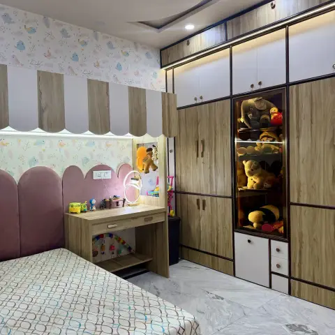 Child's bedroom with a pink arched velvet headboard against bird-print pastel wallpaper, a scalloped awning canopy over a desk lit by a ring lamp
