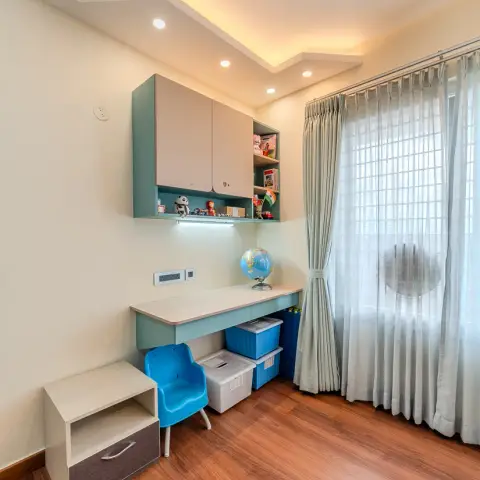 Child's built-in study nook in mint-green and cream laminate — overhead shutters with an open cubby of toys and a globe on the desk