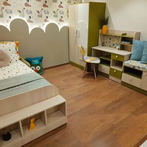 Child's room in olive and light oak - a single bed whose rounded footboard doubles as toy cubbies
