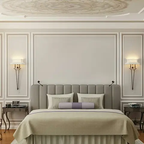 Classic bedroom with a taupe channel-tufted headboard, picture-frame wall mouldings, brass reading-arm sconces, and a painted medallion ceiling mural.