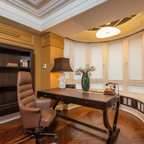 Classic home study with a dark wood writing desk and brown leather chair, a built-in bookshelf
