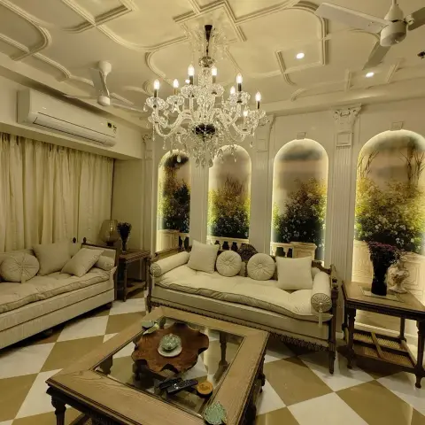 Classic living room with a crystal chandelier under a coffered pop ceiling, carved cream sofas