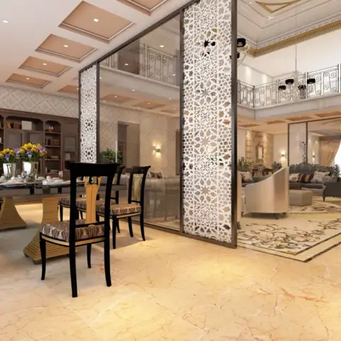 CNC-cut floral jaali columns paired with bronze mirror panels screen an eight-seater dining zone from a double-height living hall with a wrought-iron gallery
