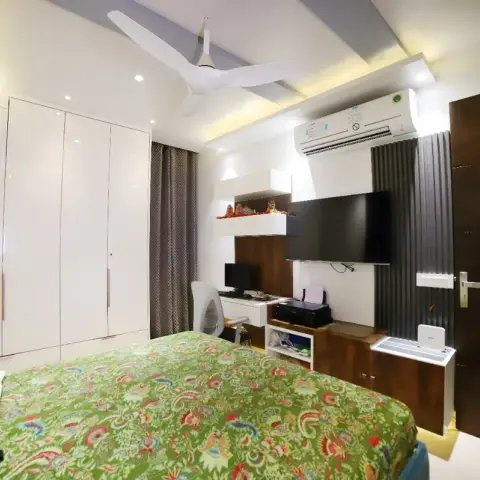 Compact bedroom where a white gloss four-shutter wardrobe faces a fluted grey TV panel