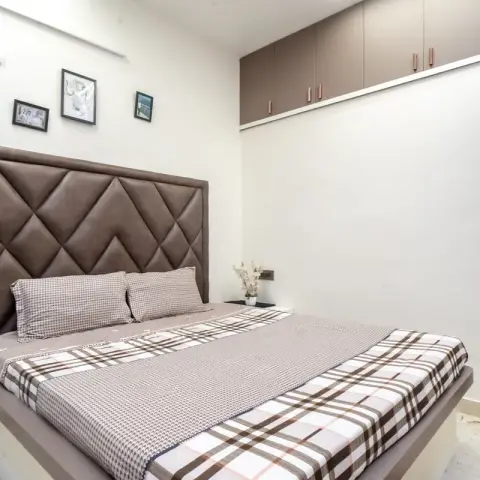 Compact bedroom with a tall diamond-tufted brown headboard on a low platform bed, brown-check bedding