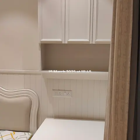 Compact kids' bedroom corner with a raised-panel wardrobe over an open shelf, a built-in study desk, and wainscot wall panelling.