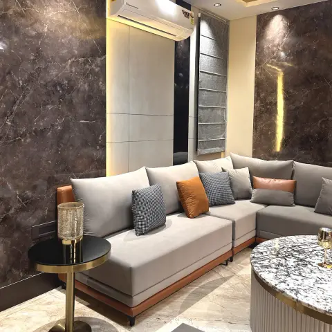 Compact living room walled in dark brown marble-effect slabs with a slim vertical gold light groove