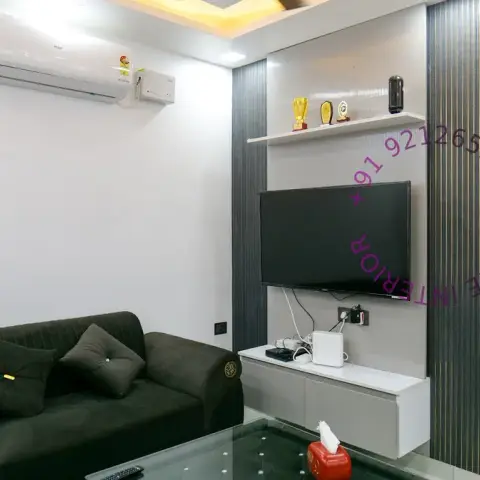 Compact living room with a grey fluted TV panel edged in thin gold reveals, trophies lined up on a white display ledge