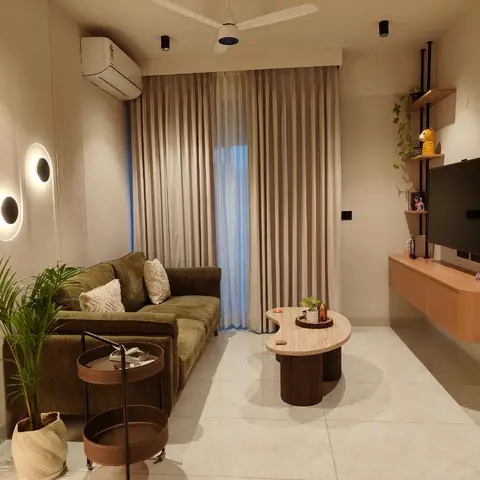 Compact living room with an olive velvet sofa, fluted wall panelling, and a floating wood TV console with round wall sconces.