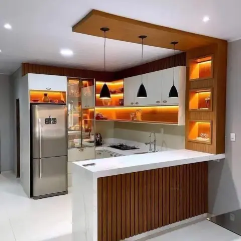 Compact open kitchen with a white waterfall-stone peninsula fronted in fluted teak, three black cone pendants dropped from a teak ceiling raft