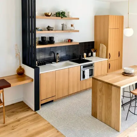 Compact wood-cabinetry kitchen with a black tile backsplash, open shelving, a built-in desk nook