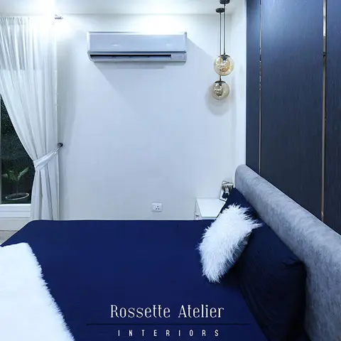 Contemporary bedroom with a navy fluted panel headboard wall edged in gold trim, amber glass drop pendant lights