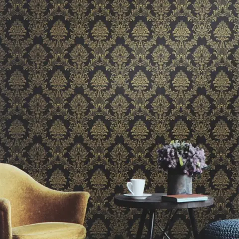 Corner nook with a black-and-gold damask wallpaper wall, a mustard velvet armchair, and a round black side table styled with coffee and flowers.
