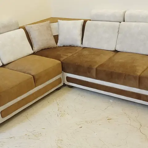Corner sectional sofa in taupe and cream suede-look upholstery set against a marble-floored living room corner