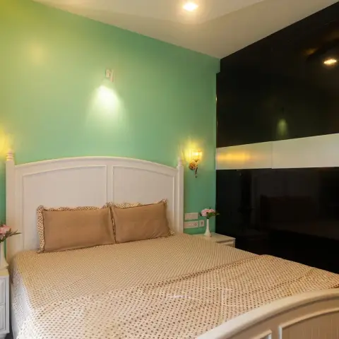 Cottage-style white beadboard bed with turned posts and matching two-drawer nightstands against a mint-green wall