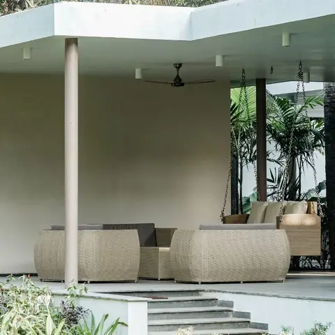 Covered outdoor veranda with woven rattan sofa seating, a hanging swing chair, a ceiling fan