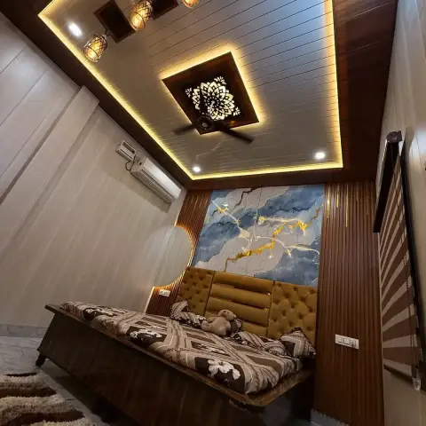 Cozy bedroom with an ornate backlit wood ceiling medallion, mustard tufted headboard, and a blue-and-gold marble-effect accent panel above a daybed-style bed.