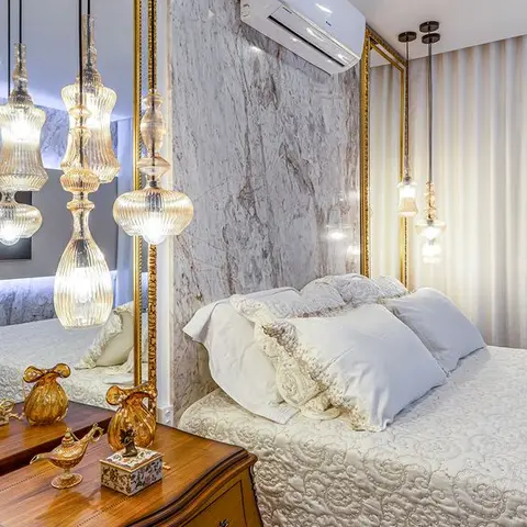 Cream bedroom corner where a grey-veined marble headboard wall is flanked by gold-framed mirror panels
