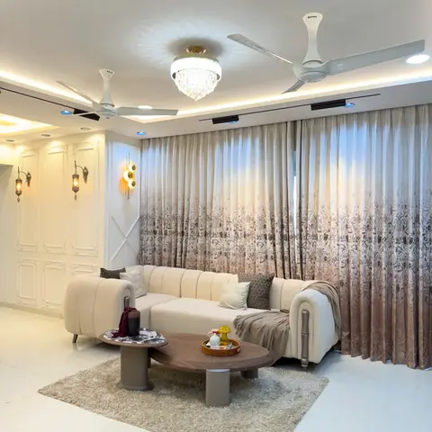 Cream chesterfield-style sectional sofa on a shaggy rug facing a two-tier round coffee table