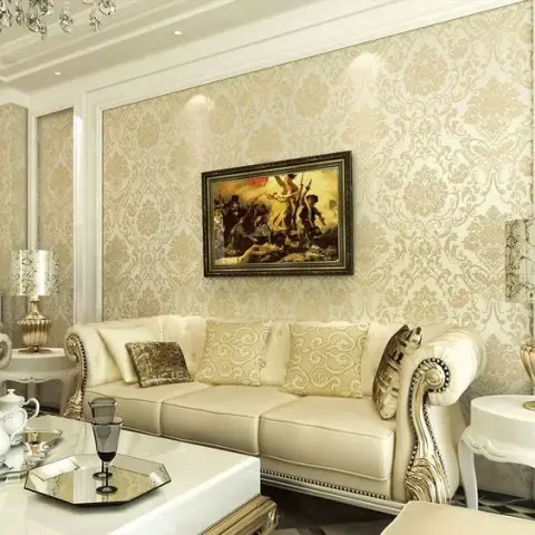 Cream damask wallpaper behind a button-tufted ivory leather sofa with carved gilt scroll arms