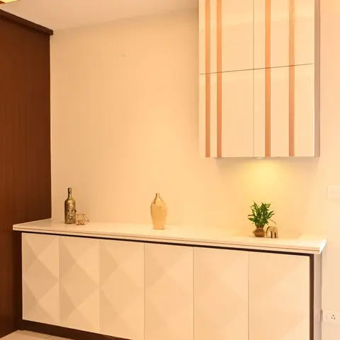 Cream dining console with a rose-gold striped floating overhead cabinet, styled with brass vases and a small potted plant.
