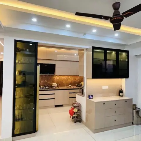 Cream high-gloss straight kitchen seen through a wide opening from the dining side