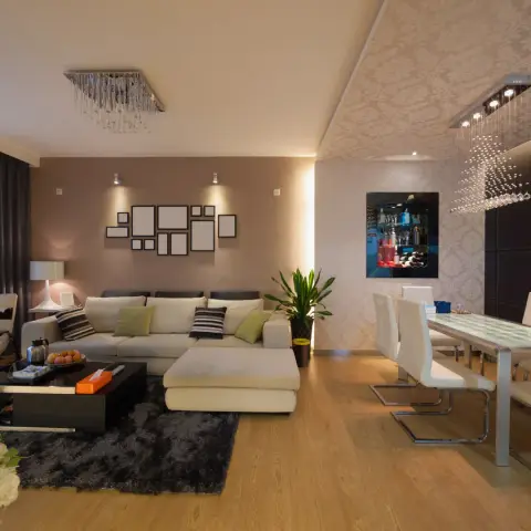 Cream L-sectional with a detached chaise sits on a charcoal shag rug under a cluster of empty black picture frames