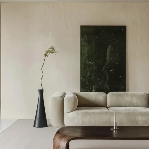 Cream lime-plastered living-room wall hung with a single dark green marble slab as artwork, above a low bouclé-textured sofa