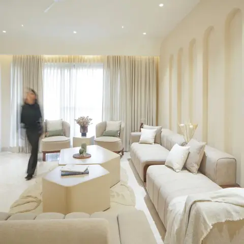 Cream-on-cream living room where shallow plaster arches run the length of one wall under two opal disc lamps
