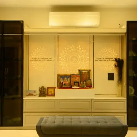 Cream pooja unit with a backlit Om-and-mandala panel and etched Sanskrit shlokas on the side shutters